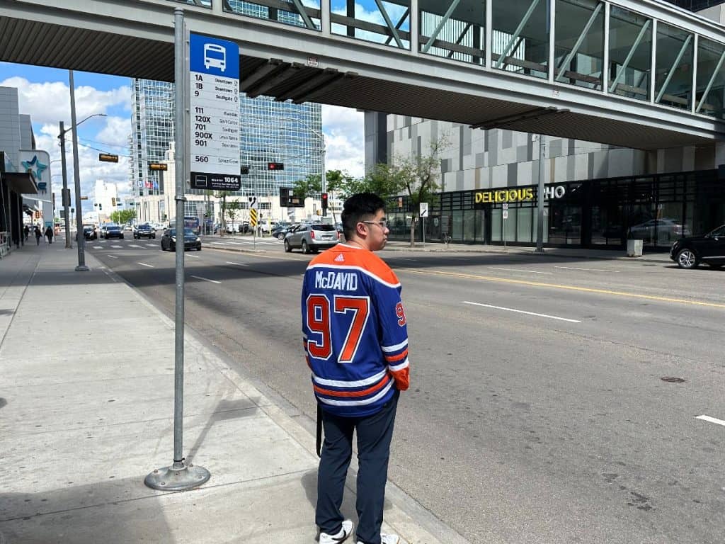 An Oilers fan waiting at an ETS bus stop