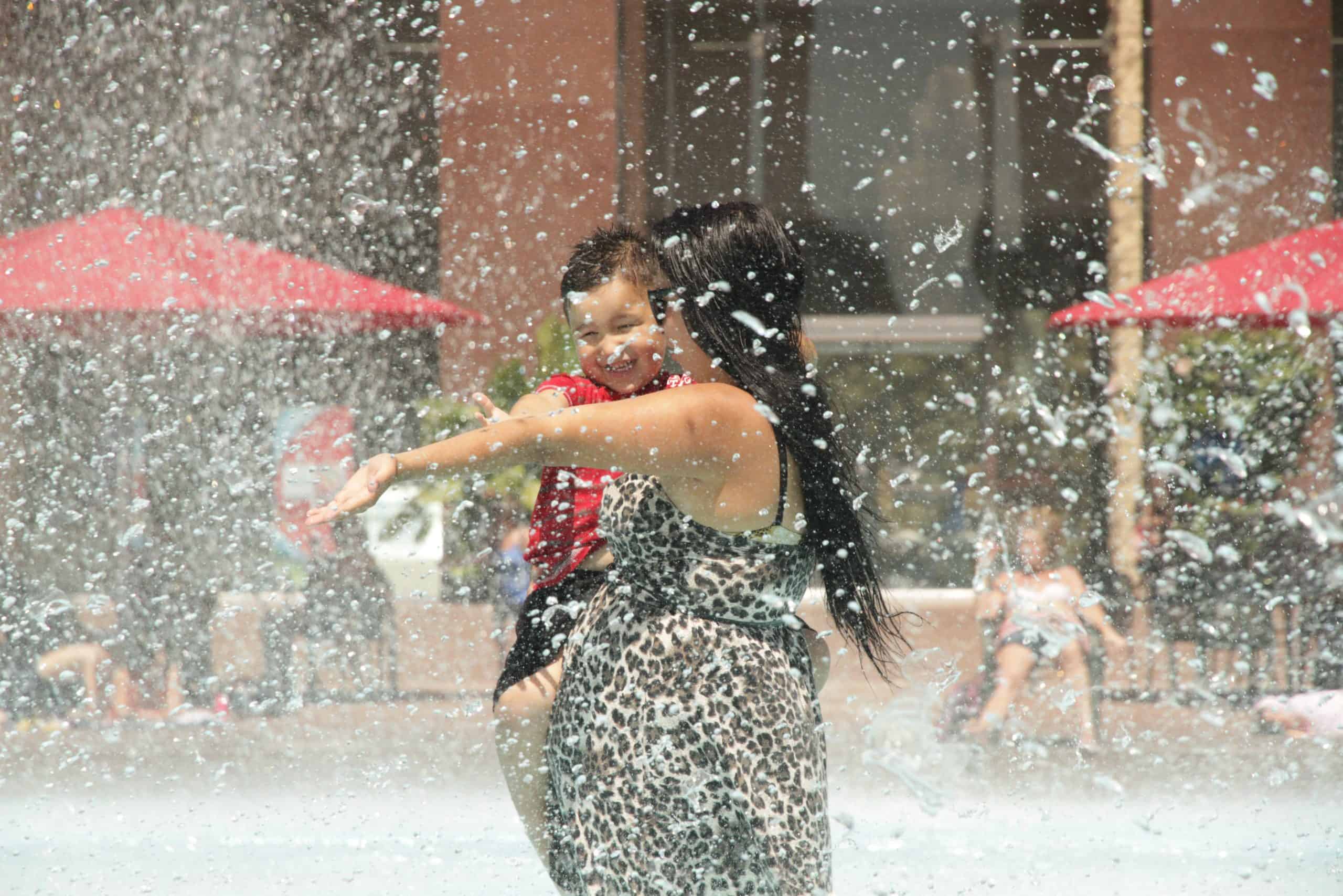 Image of people splashing in a fountain on a summer day
