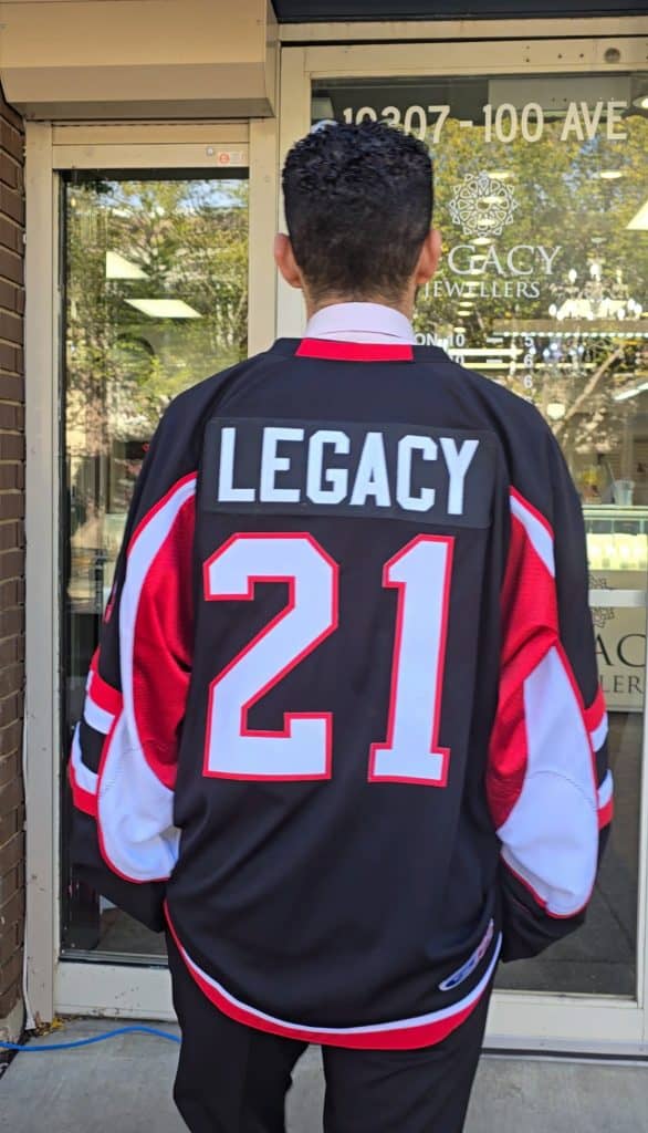 Legacy Jewellers staff member in a gifted custom jersey supporting the Fort Saskatchewan Minor Hockey Girls League, standing in front of the store entrance.