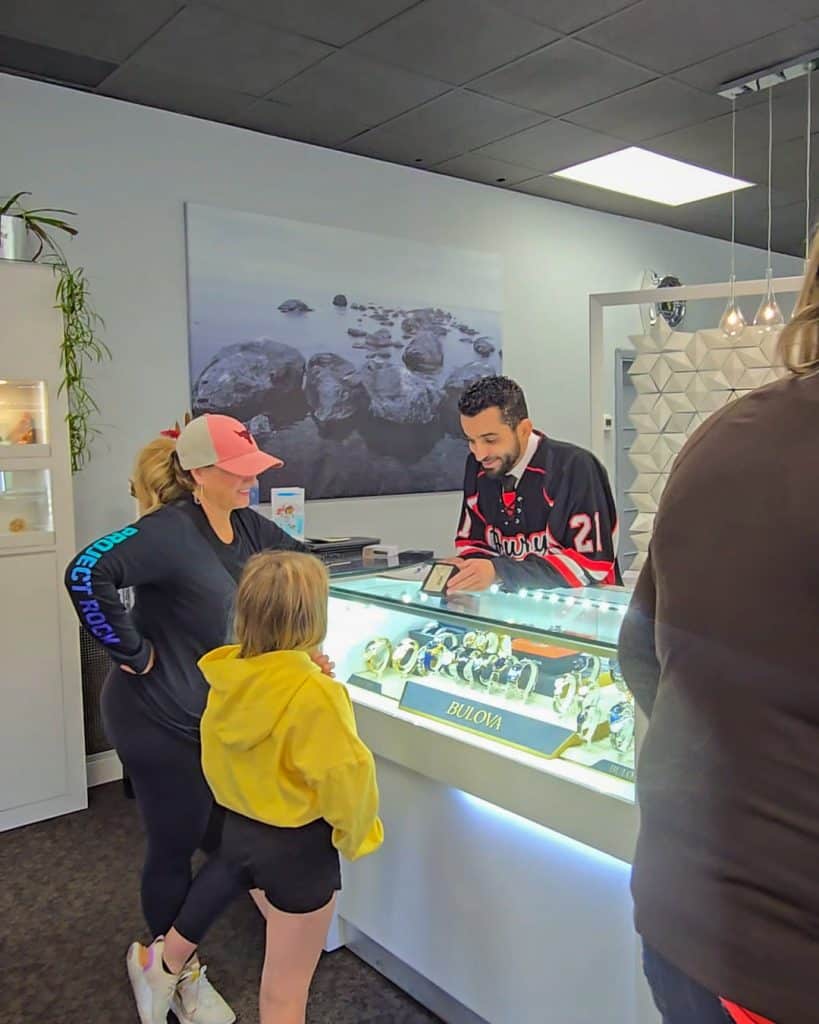 Families chatting with Legacy Jewellers staff inside the store, showcasing the jewelry collection after enjoying the BBQ outside.