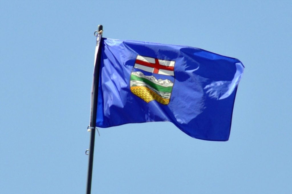 Alberta flag, flying majestically with a bright blue sky in the background.