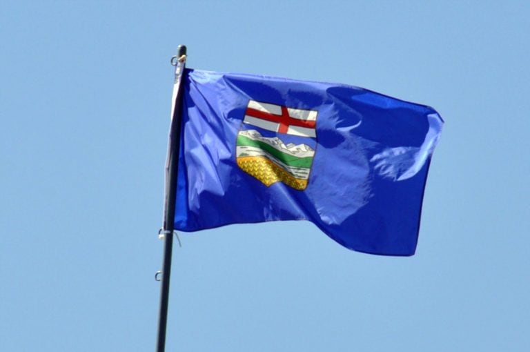Alberta flag, flying majestically with a bright blue sky in the background.